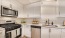 stylish kitchen in 1 bedroom apartment with white shaker cabinets, quartz countertops and high end appliances